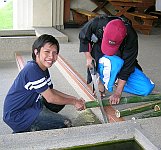 students sawing bamboo poles